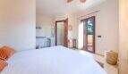 Luminoso dormitorio de la finca Portocolom con cama doble, baño en suite, ventilador de techo y acceso a terraza.