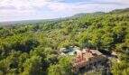 Fotografía aérea de una finca en Felanitx, rodeada de pinos y olivos, con piscina y terraza