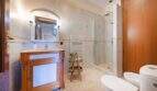 Elegante cuarto de baño de la Finca Portocolom con lavabo de madera, ducha de cristal, bidé e inodoro