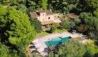 Vista aérea de una finca exclusiva en Portocolom con gran piscina, tumbonas y exuberante verdor.