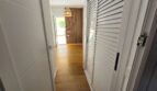 Heller Flur mit weißen Jalousietüren, Holzboden und Holzlamellenwand im Hafenapartment Portocolom