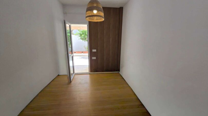 Heller Eingangsbereich mit Holzboden, Holzlamellenwand und Rattanlampe im Meereslinie-Apartment Portocolom