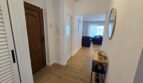 Heller Eingangsflur mit Holzboden, Rundspiegel und Blick ins Wohnzimmer des Hafenapartments in Portocolom