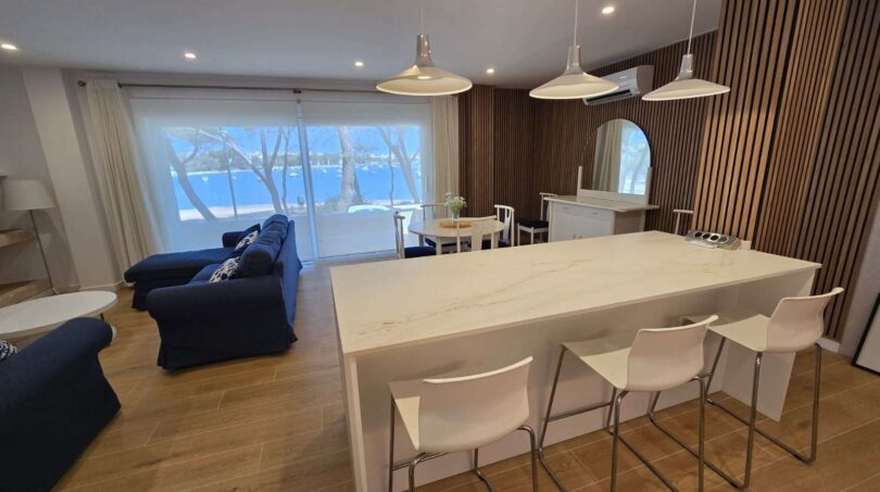 Offener Wohn-Kochbereich mit Marmor-Kücheninsel, Meerblick und Holzakzenten in Hafenapartment Portocolom