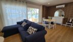 Helles Wohnzimmer mit blauem Sofa, Esstisch und Meerblick durch große Terrassentür in Portocolom