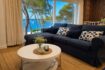 Helles Wohnzimmer mit dunkelblauem Sofa und Panoramafenster mit Meerblick auf den Hafen von Portocolom