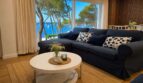 Helles Wohnzimmer mit dunkelblauem Sofa und Panoramafenster mit Meerblick auf den Hafen von Portocolom