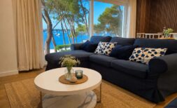 Bright Living Room with Dark Blue Sofa and Panoramic Window with Sea View of Portocolom Harbor