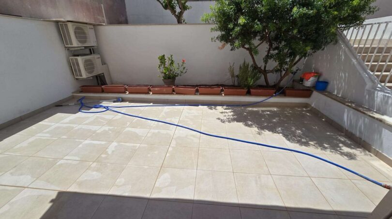 Sonnige Dachterrasse mit Fliesenboden, Klimaanlagen, Topfpflanzen und Baum in Portocolom