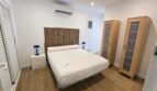 Helles Schlafzimmer mit Doppelbett, Holzkopfteil, Klimaanlage und zwei Holzschränken im Hafenapartment Portocolom