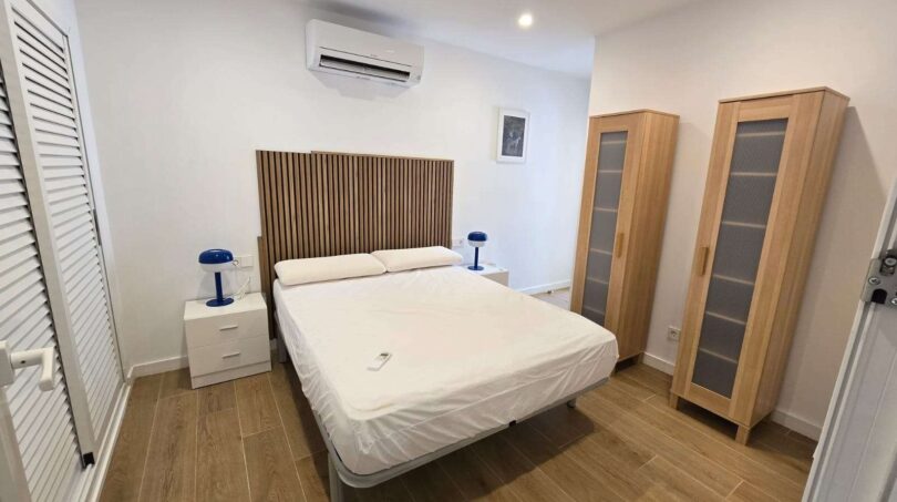 Helles Schlafzimmer mit Doppelbett, Holzkopfteil, Klimaanlage und zwei Holzschränken im Hafenapartment Portocolom