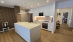 Moderne weiße Küche mit Kücheninsel, Marmor-Arbeitsplatte und Holzboden im Hafenapartment Portocolom
