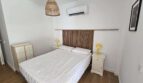 Helles Schlafzimmer mit Doppelbett, Holzkopfteil, gelben Nachttischlampen und Klimaanlage im Hafenapartment Portocolom