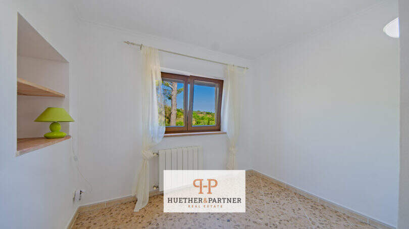 Helles Schlafzimmer der Finca Son Macià mit Einbauregal, Heizkörper und Fenster mit Gartenblick