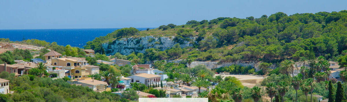 Panoramablick auf Cala Romántica mit Meer, Pinienwald und mediterraner Bebauung in Porto Cristo Novo