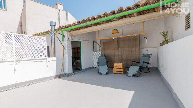 Dachterrasse des Herrenhauses in Porreres mit zwei Liegestühlen, Terrakottadach und grüner Regenrinne unter blauem Himmel.