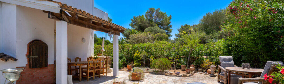 Sonnige Terrasse mit Liegestühlen, überdachtem Essbereich und üppigem Garten in Cala Murada