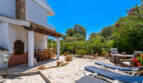 Sonnige Terrasse mit Liegestühlen, überdachtem Essbereich und üppigem Garten in Cala Murada