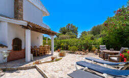 Sonnige Terrasse mit Liegestühlen, überdachtem Essbereich und üppigem Garten in Cala Murada