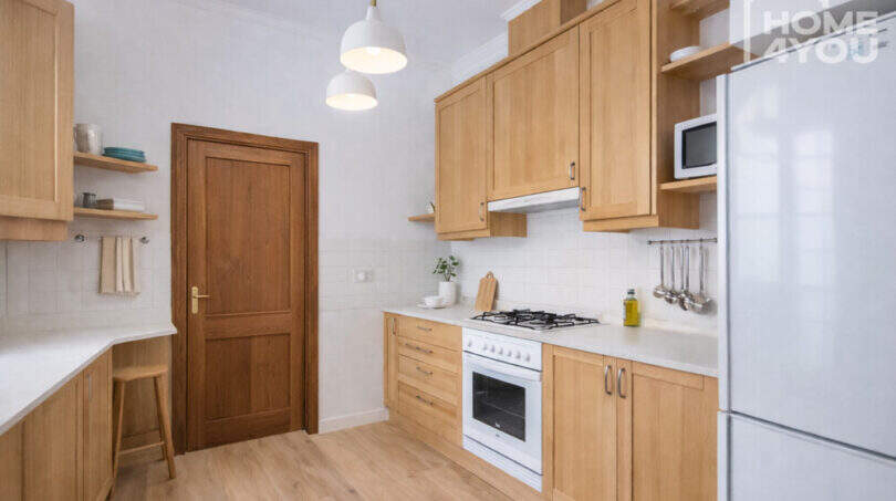 Helle Küche mit Holzschränken, Gasherd, Kühlschrank und Pendelleuchten im historischen Herrenhaus in Porreres.