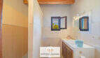 Badezimmer der Finca Felanitx mit Waschbecken, Bidet, Holzbalkendecke und kleinem Fenster mit Naturblick