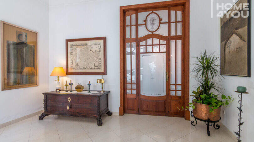 Eleganter Eingangsbereich mit historischer Holztür, antikem Truhenkommode und Kunstwerken im Herrenhaus Porreres