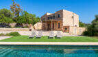 Rustikale Naturstein-Finca in Cales de Mallorca mit türkisem Pool, Liegestühlen und gepflegtem Gartenbereich.