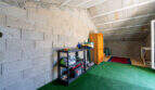 Garage mit Betonwänden, Holzschrank, Regalen und grünem Kunstrasenboden in Doppelhaus Cala Murada