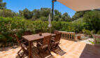 Sonnige Terrasse mit Holzmöbeln und üppigem Grün in Cala Murada