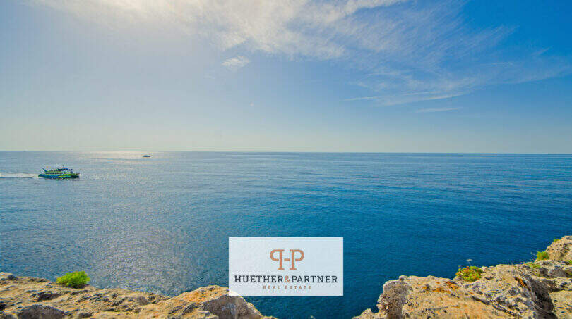 Atemberaubender Meerblick in 1. Linie Porto Cristo: Tiefblaues Mittelmeer, Klippen und Fährschiff am Horizont.