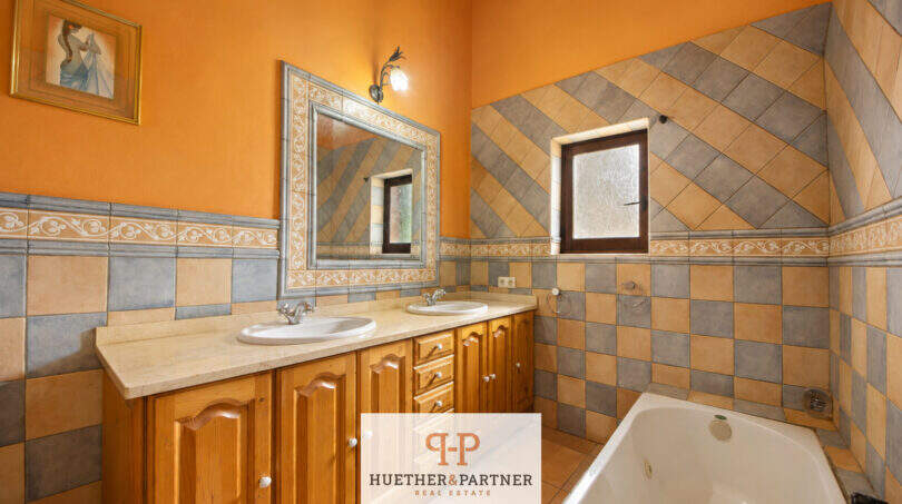 Badezimmer der Finca Felanitx mit Doppelwaschbecken, Whirlpool-Badewanne und dekorativen Wandfliesen