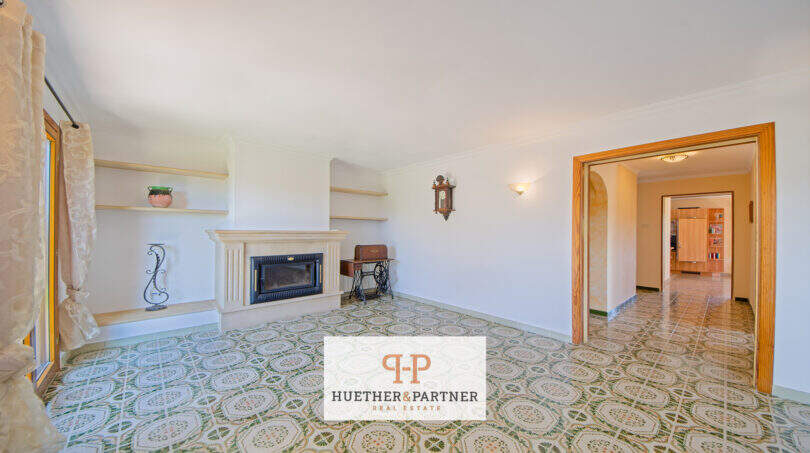 Helles Wohnzimmer der Finca Son Macià mit Kamin, Mosaikfliesen und Durchgang zum Flur.