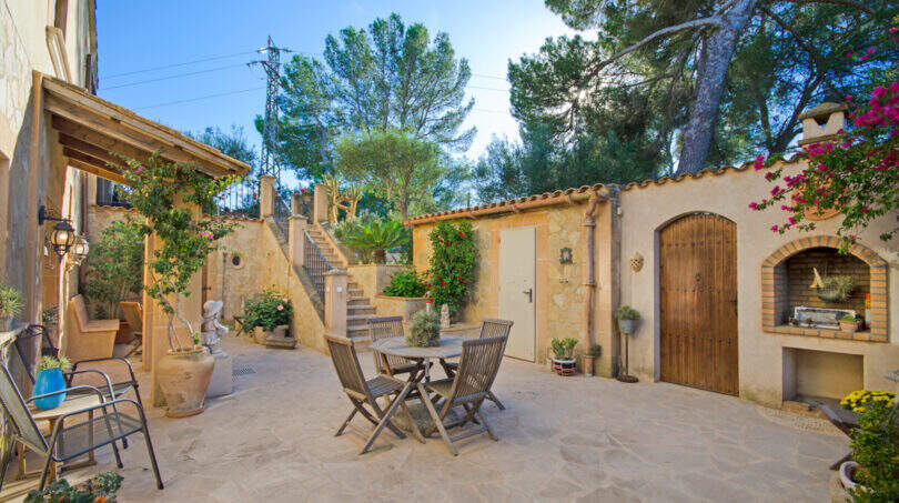 Sonniger Innenhof der Finca Son Macià mit Sitzgruppe, Grillnische und mediterranem Bepflanzung