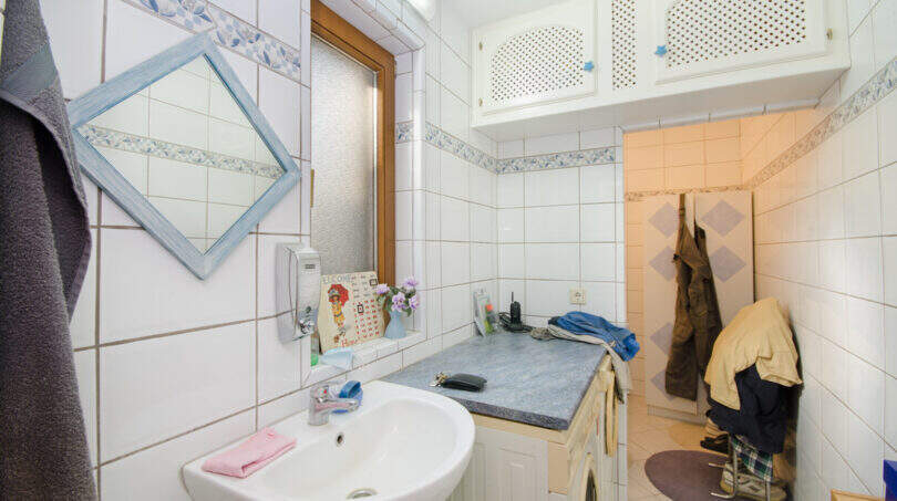 Helles Badezimmer der Finca in Son Macià mit Waschbecken, Spiegel, Waschmaschine und weißen Fliesen.