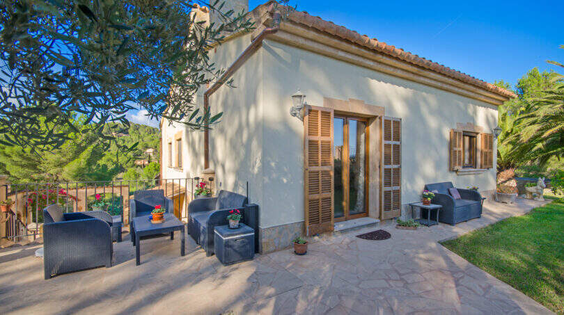 Sonnige Terrasse der Finca Son Macià mit Rattanmöbeln, Natursteinboden und mediterranem Garten