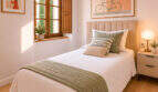 Helles Schlafzimmer im Herrenhaus Porreres mit Holzfensterläden, Doppelbett und mediterranem Kunstwerk