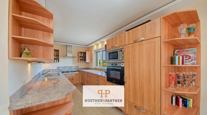 Helle Einbauküche mit Holzfronten, Granitarbeitsplatte, Backofen und offenen Regalen in Finca Son Macià