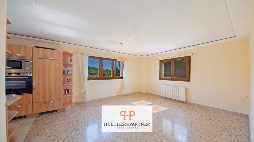 Helles Wohnzimmer der Finca Son Macià mit Einbauküche, Terrazzoböden und großen Fenstern mit Naturblick