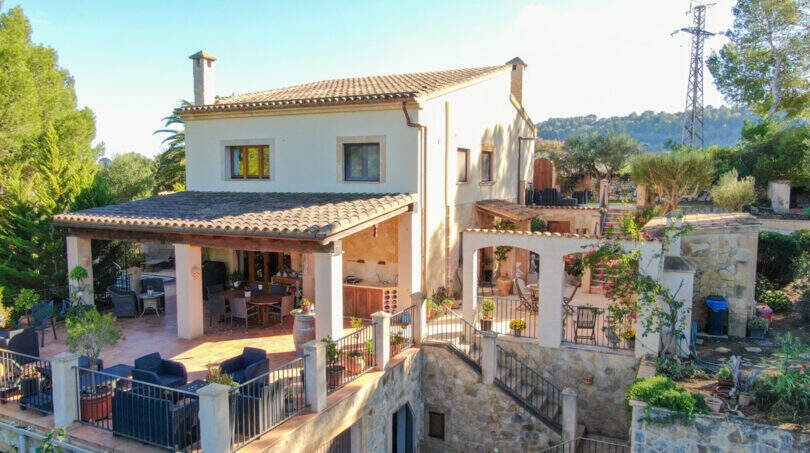 Mediterrane Finca in Son Macià mit Terasse, Pergola, Naturstein und üppigem Grün – traumhafte Außenansicht.