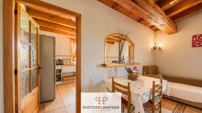 Rustikales Esszimmer der Finca Felanitx mit Holzbalkendecke, Esstisch und Blick in die Küche