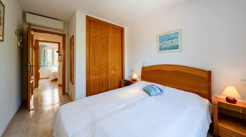 Helles Schlafzimmer mit Doppelbett, Holzeinbauschrank und Klimaanlage im Doppelhaus Cala Murada.