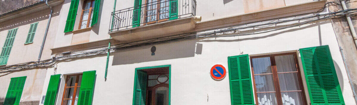 Historisches Herrenhaus in Porreres: Gepflegte Fassade mit grünen Fensterläden, Balkon und elegantem Holzeingangsportal.