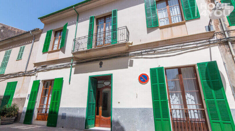 Historisches Herrenhaus in Porreres: Gepflegte Fassade mit grünen Fensterläden, Balkon und elegantem Holzeingangsportal.