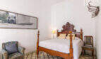 Schlafzimmer mit antikem Holzbett, Ornamentkopfteil, Mosaikfliesenboden und historischem Charme im Herrenhaus Porreres