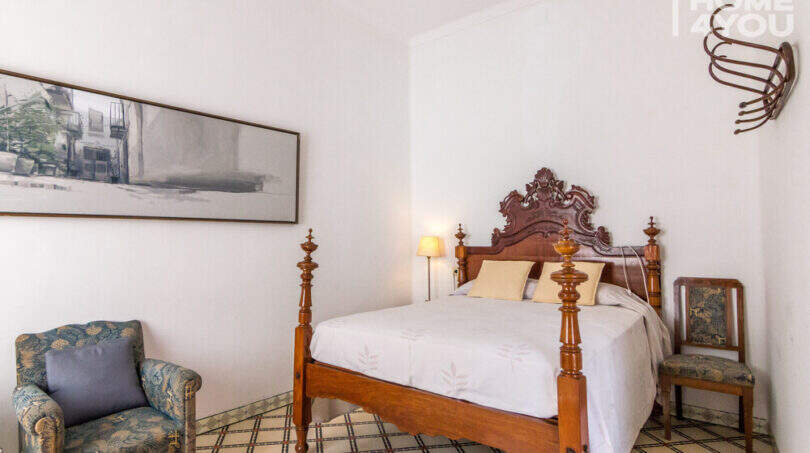 Schlafzimmer mit antikem Holzbett, Ornamentkopfteil, Mosaikfliesenboden und historischem Charme im Herrenhaus Porreres