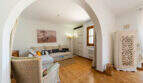 Wohnzimmer mit Rundbogen, Korbsessel, hellem Sofa, Holzboden und weißem Vintage-Schrank in Cala Murada