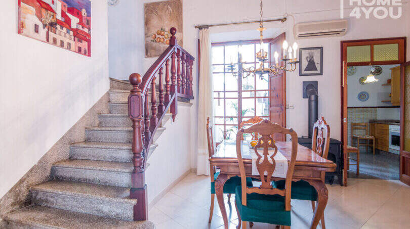 Esszimmer mit Holztreppe, Kronleuchter, Esstisch und Blick in Küche im historischen Herrenhaus in Porreres