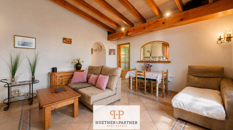 Helles Wohnzimmer der Finca Felanitx mit Holzbalkendecke, Sandsteinfliesen und rustikaler Einrichtung.