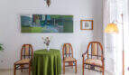 Elegantes Wohnzimmer im Herrenhaus Porreres mit antiken Holzstühlen, grünem Rundtisch und Gemälde an weißer Wand