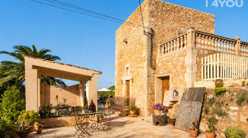 Rustikale Natursteinfassade mit Terrasse, Pergola und mediterranem Pflanzendekor des Agroturismo bei Ses Salines